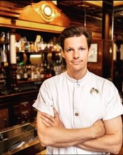 Hombre parado en un restauranteDescripción generada automáticamente
